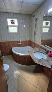 Un baño con dos lavabos, una bañera y un espejo. en Splendid Private Rooms, en Sharjah