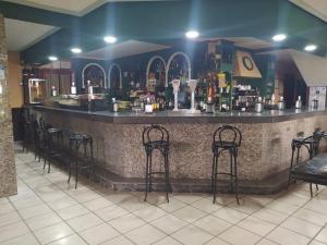 a bar with black stools in a restaurant at Pensión El Chalet in Torrejoncillo del Rey