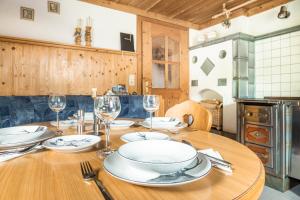 a wooden table with plates and wine glasses on it at Panorama Chalet Höllmaishof in Bischofshofen