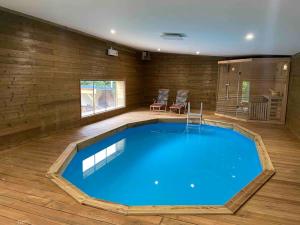 a large blue swimming pool in a room with wooden floors at Magnifique maison spa in Aix-en-Ergny