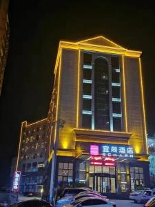 咸宁宜尚酒店(通山牛头山公园店)的一座有照明的建筑,前面有汽车停放