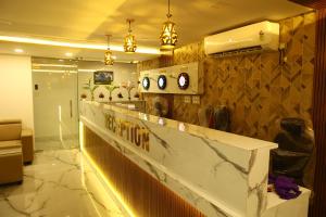 a lobby with a counter with clocks on the wall at Grand Tamim Hotel in Mangalore