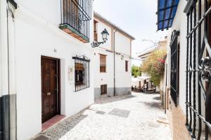 an alley with white buildings and a brown door at Wekey Homes, Casa del Albaicyn in Granada