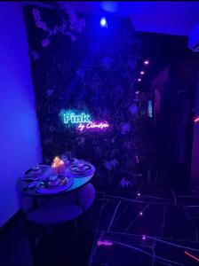a table with a candle in front of a neon sign at Le Pink in Aubervilliers