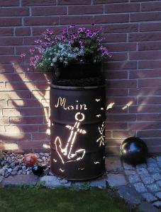 Una jardinera con una maceta con flores dentro en Ferienwohnung Im Landhaus, en Stelle-Wittenwurth