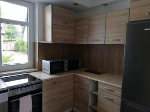 a kitchen with wooden cabinets and a microwave and a window at Pokoje u Iwonki - Barzowice in Barzowice