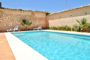 una piscina con due sedie accanto a un edificio di Casas Rurales Los Teatinos a Casas de los Teatinos