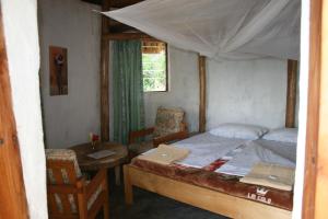 1 dormitorio con 1 cama, mesa y sillas en Amasiko Homestay Lake Bunyonyi, en Kabale