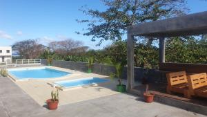 a swimming pool with two chairs and a pavilion at The confidence in Mahébourg