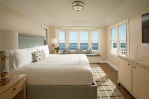 a bedroom with a large white bed and windows at Chatham Bars Inn in Chatham