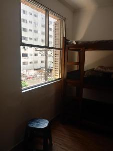 a bedroom with a window with a bunk bed and a stool at APMartinsjreige in São Vicente