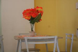 a table with a vase with red flowers on it at Appartement à 15min de belles plages in Sainte-Rose