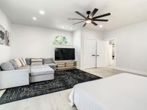 a white living room with a couch and a television at Cozy Getaway Home - near Siesta Key Beach in Sarasota
