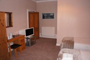 a bedroom with a bed and a desk with a television at Camillia Guest House in Aberdeen