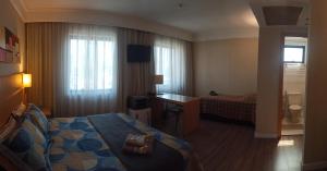 a hotel room with a bed and a desk at Hotel Flat Guarulhos Apto1411 in Guarulhos