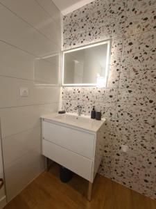Un baño blanco con lavabo y espejo. en Le Nid du Bosquet, en Issoire 6 fotos más