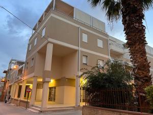 a building on a street with a palm tree at Casa Trieste in Pozzallo