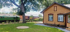 a small house and a green train next to a building at Vilties vila in Anykščiai