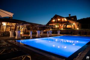 a swimming pool at night with chairs and umbrellas at Villa Djuric in Slatina Varoš