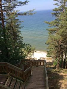 a wooden boardwalk leading to a beach with trees at Sea View Slavia in Międzyzdroje