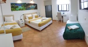 a bedroom with two beds and a table and a desk at A Caminho da Ilha in Ponta Delgada