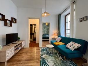 a living room with a blue couch and a tv at Le Petit Moulin in Montbéliard