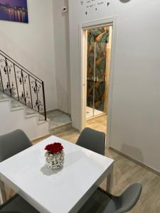 a white table with a vase with red flowers on it at La Petite Maison in Naples