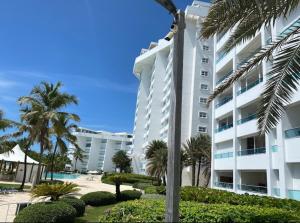 a large white building with palm trees and a swimming pool at Beachfront Apartment with Jacuzzi in Juan Pedro
