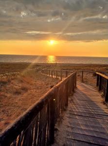 drewniany deptak prowadzący na plażę o zachodzie słońca w obiekcie Villa Patio Capbreton w mieście Capbreton