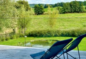 a couple of chairs on a deck with a view of a pond at Saules et Têtards in Frasnes-lez-Anvaing