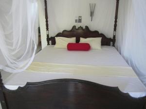 Una cama con una almohada roja encima. en Serene Niche, en Mirissa