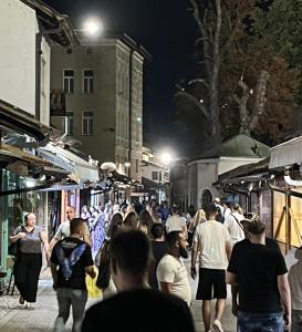 a crowd of people walking down a street at night at Sarajevo Luxury Apartment - 50 m from Old Sarajevo Clock Tower in Sarajevo