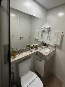 a bathroom with a toilet and a sink and a mirror at Caminho do Mar - Apartamento com excelente localização in Rio das Ostras