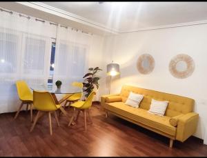 a living room with a yellow couch and a table at Apartamento céntrico con Wifi Avilés in Avilés