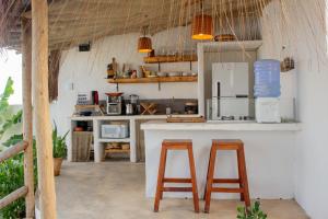 a kitchen with two bar stools and a refrigerator at Araxá Milagres in São Miguel dos Milagres