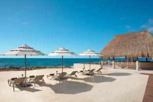een groep stoelen en parasols op een strand bij Dreams Aventuras Riviera Maya - All Inclusive in Puerto Aventuras