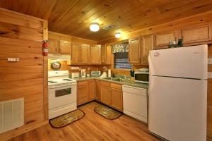 a kitchen with a white refrigerator and wooden cabinets at Private Paradise #2810 in Pigeon Forge