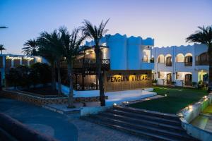 a building with palm trees in front of it at Penguin Village Dahab in Dahab