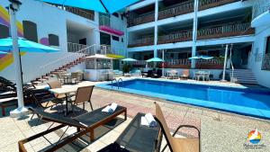 a swimming pool with chairs and tables next to a building at Hotel Paloma del Mar in Puerto Vallarta