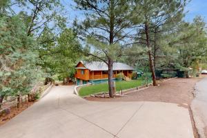 a house with a tree in front of a driveway at Lakeside Livin' in Pinetop-Lakeside