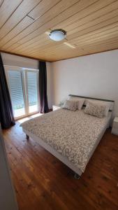 a bedroom with a bed with a wooden ceiling and windows at Planinska kuća Rezo Rakitno in Posušje