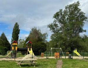 a park with a playground with a slide and swings at Ivry calme détente piscine sport famille by Vayny in Ivry-la-Bataille