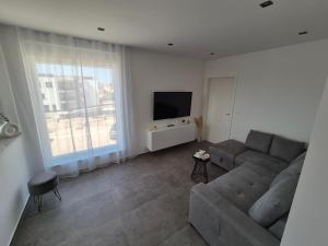 a living room with a couch and a flat screen tv at Adriatic Wave Residence in Brodarica