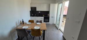 a kitchen with a wooden table with chairs and a dining room at Adriatic Wave Residence in Brodarica