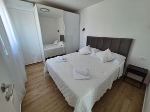 a bedroom with a bed with white sheets and a mirror at Adriatic Wave Residence in Brodarica
