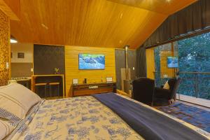 a bedroom with a bed and a desk and a television at Requinte dos Pinhais Chalé in Santo Antônio do Pinhal