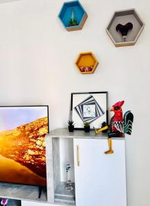 a table with a tv on a wall with pictures at NOZA Appartement 65m2, 2 chambres - RDC, Parking gratuit, Nantes agglo Rezé in Rezé