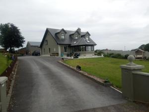 una casa con un cane seduto sul ciglio di una strada di Blackbrink cottage a Roscommon