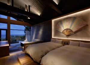 two beds in a room with a fan on the wall at 間人温泉 炭平 in Kyotango