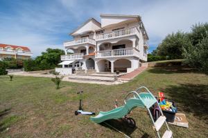 a large white house with a playground in the yard at Apartment Povljana 224d in Povljana